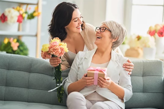 Dotter som ger sin mamma blommor på mors dag